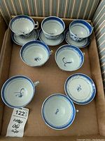 Top view of teacups and saucers arranged in box, showing blue and white porcelain with Dutch Delft style painting.