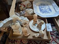 Box displaying eagle figurine, frog figurine, four children figurines, decorative plate, and floral ceramic trinket dish.