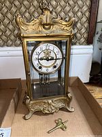 Front view of brass and glass mantel clock with winding key placed in front