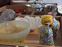Overview of Murano glass decorative items including frosted bowl, white swirled bowl, clown figurine, vases, metallic cups, and lidded containers.