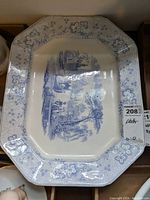 Top-down image showing the entire platter with blue and white scenic design and floral border pattern.
