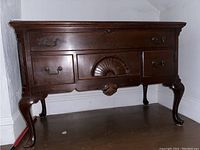 Front view of wooden blanket box showing cabriole legs, multiple drawers, and carved fan detail on middle drawer.