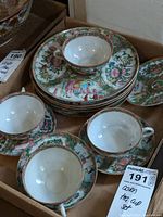 Set of four teacups with handles, four matching saucers, and four small decorated plates all in a cardboard box.