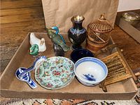 Lot overview featuring various vintage ceramic bird figurines, Asian soup spoons, bowls, vase, miniature bird cage, and wooden tool.