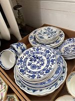Top view photo showing stacks of blue and white patterned plates and teacups in a box.