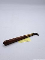 Full view of the vintage agate burnisher showing wooden handle, brass collar, and curved stone tip
