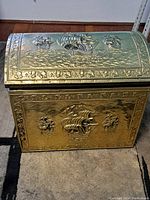 Full view of the brass chest showing the embossed ship designs on the front and lid.