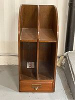 Front view of the wooden desk/file organizer showing two vertical compartments and a single bottom drawer with brass handle.