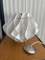 Side view of hanging light fixture showing curved white panels forming shade