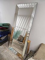Full view of the large rectangular mirror resting on floor showing its beveled mirrored frame and reflective surface.