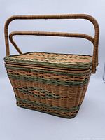 Front and side view of the large wicker picnic basket showing the dual handles and woven natural with green accented wicker exterior.
