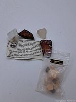 Photo showing various mineral samples including borite, a white porous mineral, and some Australian opals in a labeled plastic bag, along with an informational leaflet about borite mineral properties.