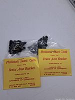 Photo of two sealed plastic bags each containing multiple prehistoric shark teeth with accompanying yellow labels from Venice Area Chamber of Commerce.