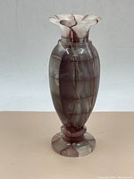 Front angle view of the stone vase showing the flared rim and checkered reddish-brown and gray colors.