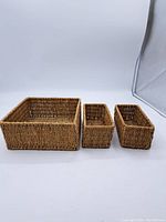 Photo showing all three woven baskets arranged side by side, large square basket on left and two narrow rectangular baskets on right.