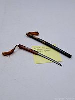 Two mini samurai sword letter openers with decorative handles and tassels.