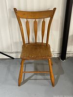 Front view of vintage wood chair showing the full front profile with curved backrest and four vertical spindles
