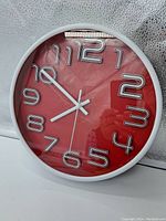 Front view of the vintage red wall clock showing white modern 3D numbers and white hands.