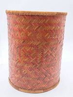 Front view showing cylindrical shape and reddish-brown woven herringbone wicker pattern.