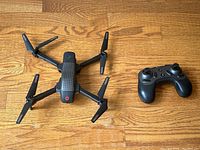 Top-down view of the Ascend Aeronautics drone and wireless remote controller on wooden floor.