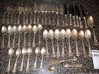 Overall layout of flatware on countertop showing forks, knives, spoons and serving pieces