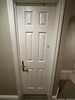 Full view of the white interior door installed in a frame, showing six-panel design.