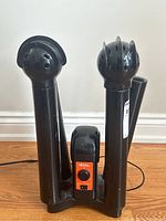 Front view of black plastic Little Hotties electric drier with two upright drying tubes and orange control panel.