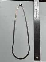 Full view of serpentine chain necklace alongside a ruler showing length.
