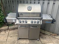 Front view of the full Napoleon Legend Series stainless steel BBQ grill showing double doors, side shelves, and control panel with five knobs.