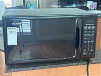 Front view of the black Panasonic microwave oven with keypad buttons and handle on the right side of the door.