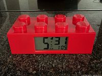Front view showing the time on the digital LCD display embedded in the red LEGO brick-shaped clock.