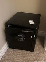 Black Sentry Safe positioned against a wall, showing its overall square shape and front door slightly open.