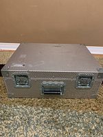 Front view of closed large aluminum case showing latches and handle.
