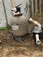 Outdoor setup showing Hayward ProSeries sand filter and connected plumbing on ground with dirt and rocks.