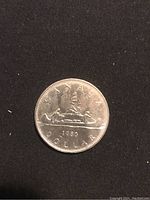 Obverse side showing the date 1980, the word 'Canada', and a canoe with two paddlers and pine trees.