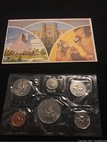 View of the front side of the lot showing the seven Canadian coins from 1984 sealed in plastic along with a color fold-out card with images.