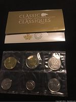 Gold and white envelope marked Classic Collection 2018 with six Canadian uncirculated coins sealed in plastic blister packaging: $1, $2, quarter, dime, nickel, and penny.