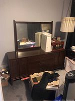 Front view of dark wood dresser with attached mirror and items placed on top