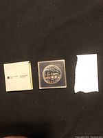 Entire lot including Royal Canadian Mint original box, plastic case with silver dollar coin, and handwritten paper with number.