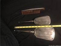 Three items of a vintage dresser set shown including a handheld mirror with a sterling silver handle, a clothes brush with a similar silver handle, and a wooden comb with missing teeth. The mirror glass is slightly loose.