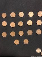 Top view of 17 old Canadian pennies on black background, showing maple leaf design.