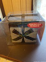 Photo of the cosmetic bag set in original clear plastic packaging, showing the houndstooth print and bow detail of one bag.