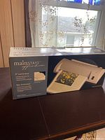 Front view of the Mainstays 9-inch laminator and 9-pocket animator set box on table with window background.