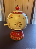Front view of the apple baker showing holiday design details and the apple-shaped handle on the lid