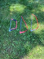 Three bow saws laid out on grass in varying sizes and colors (red-orange frames).