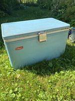 Front and top view of vintage baby blue Coleman cooler with metal latch and Coleman label.