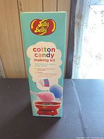 Photo of the front side of the box showing the Jelly Belly Cotton Candy Making Kit logo, product information including a picture of the cotton candy maker and cotton candy cones.