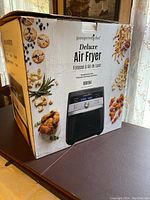 Pampered Chef Deluxe Air Fryer boxed showing air fryer image and food examples.