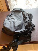 Top view showing front side of black Merrell shoulder bag with visible logo and water bottle pouch on the side.
