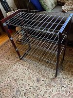 Front view of the wood framed shoe shelf showing three metal wire shelves and wood side supports